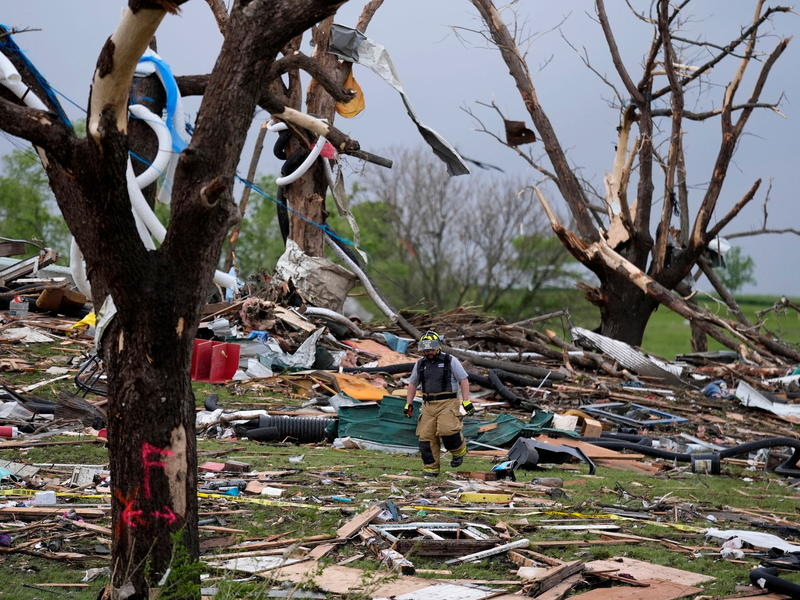 Ein Feuerwehrmann geht in Greenfield, Iowa, durch die Trümmer von Häusern, die vo einem Tornado zerstört wurden. - Foto: Charlie Neibergall/AP/dpa