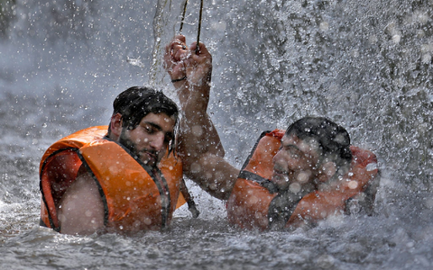 Zwei pakistanische Männer kühlen sich in Islamabad in einem Bach ab. - Foto: Anjum Naveed/AP/dpa