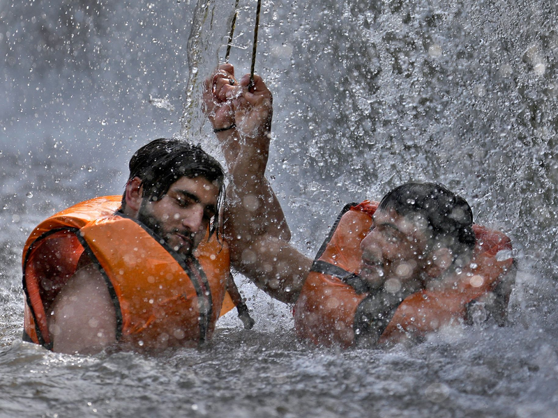 Zwei pakistanische Männer kühlen sich in Islamabad in einem Bach ab. - Foto: Anjum Naveed/AP/dpa