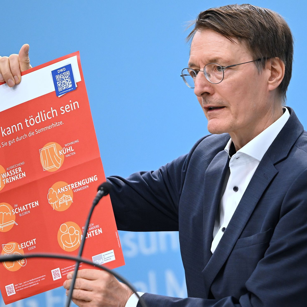 Bundesgesundheitsminister Karl Lauterbach (SPD) hält ein Plakat zum Thema Hitzeschutz hoch. - Foto: Britta Pedersen/dpa