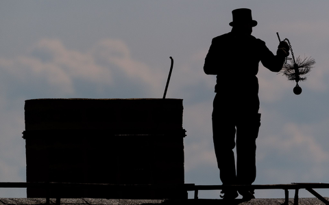 Ein Schornsteinfeger mit seinem Kaminkehrerwerkzeug auf einem Dach. - Foto: Robert Michael/dpa