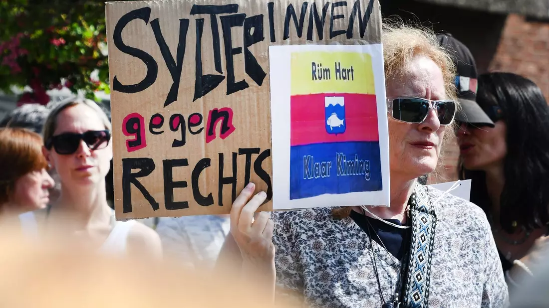Dutzende Menschen versammeln sich zu einer Mahnwache auf Sylt. Sie wollen ein Zeichen gegen Rechtsextremismus setzen. - Bild: Lea Sarah Albert/dpa