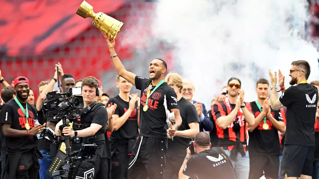 Leverkusens Jonathan Tah (M) präsentiert bei der Meisterfeier in der BayArena die Meisterschale und den Pokal. - Bild: Marius Becker/dpa