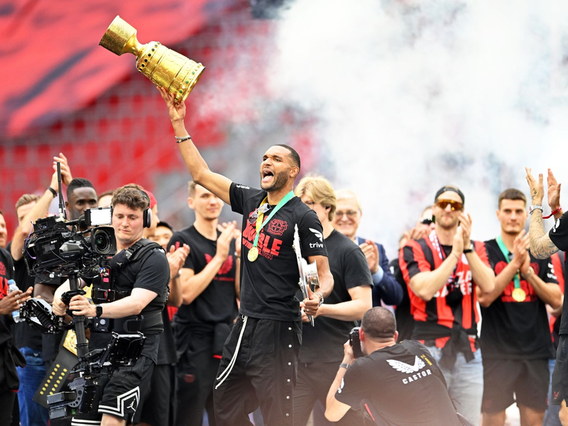 Leverkusens Jonathan Tah (M) präsentiert bei der Meisterfeier in der BayArena die Meisterschale und den Pokal. - Foto: Marius Becker/dpa