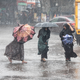 Frauen gehen bei Regen über eine Straße in Bangladesch. - Foto: Md. Rakibul Hasan/ZUMA Press Wire/dpa