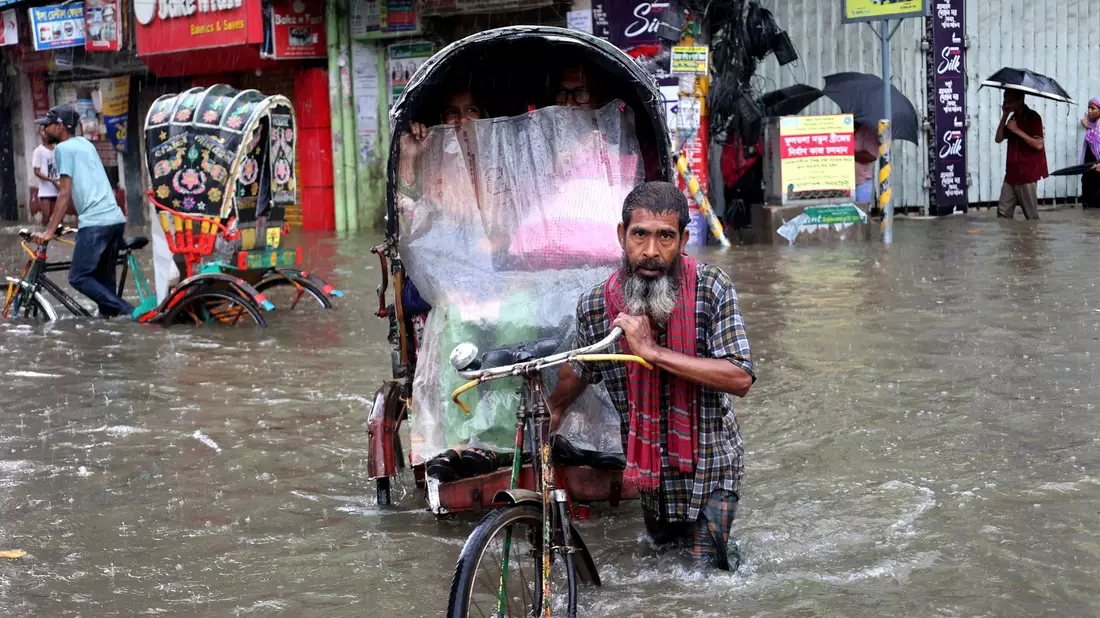 Menschen bewegen sich mühsam durch das Hochwasser in der Stadt Chittagon. - Bild: Mohammed Shajahan/ZUMA Press Wire/dpa