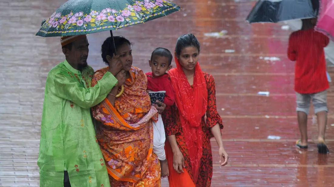 Fußgängerinnen gehen in Bangladesh durch den Regen. - Bild: Md Rafayat Haque Khan/ZUMA Press Wire/dpa