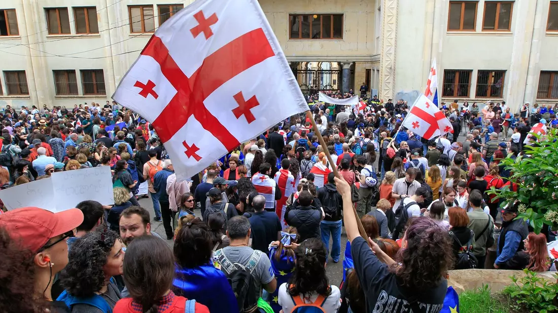 Demonstrantinnen und Demonstranten schwenken vor dem Parlamentsgebäude in Tiflis georgische Nationalflaggen. - Bild: Shakh Aivazov/AP/dpa