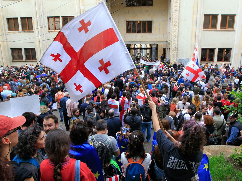 Demonstrantinnen und Demonstranten schwenken vor dem Parlamentsgebäude in Tiflis georgische Nationalflaggen. - Foto: Shakh Aivazov/AP/dpa