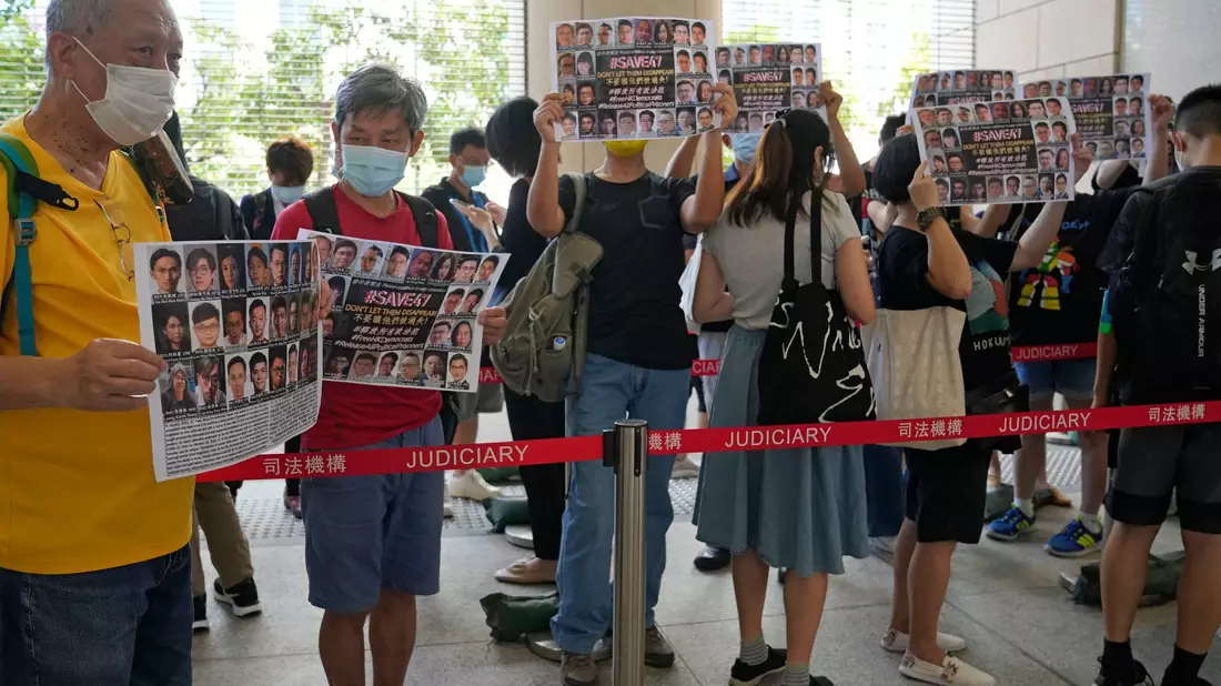 Unterstützer halten vor einem Gericht in Hongkong Plakate mit den Fotos einiger der 47 angeklagten Demokratie-Aktivisten in die Höhe. - Bild: Kin Cheung/AP/dpa