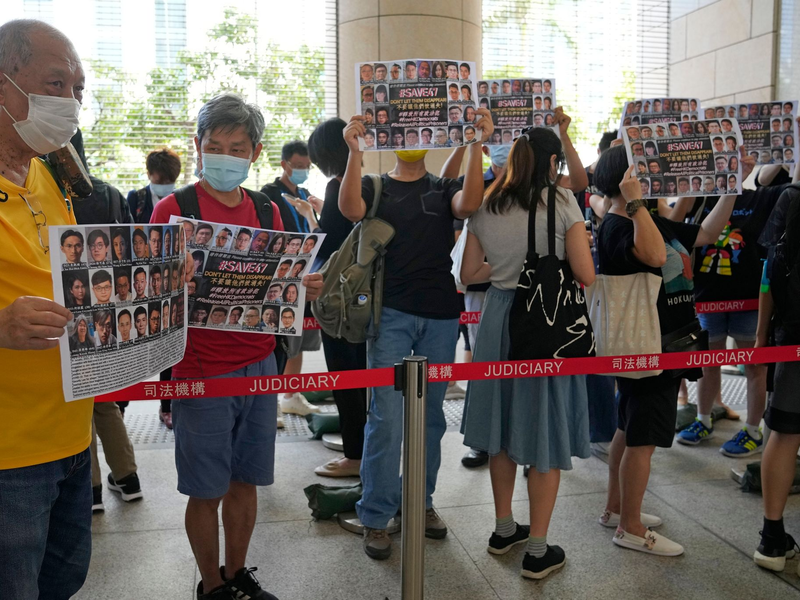 Unterstützer halten vor einem Gericht in Hongkong Plakate mit den Fotos einiger der 47 angeklagten Demokratie-Aktivisten in die Höhe. - Foto: Kin Cheung/AP/dpa