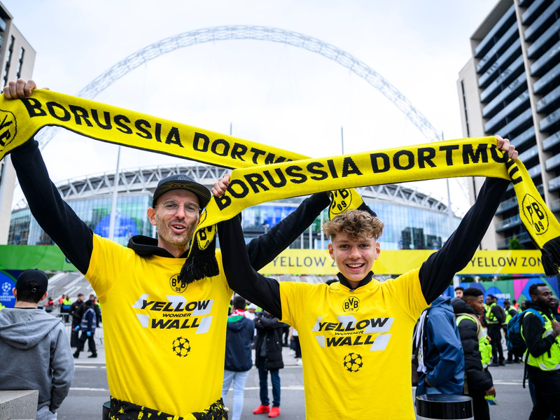 Zwei Fans von Borussia Dortmund stehen mit einem BVB-Fan-Schal vor dem Wembley-Stadion. - Foto: Tom Weller/dpa