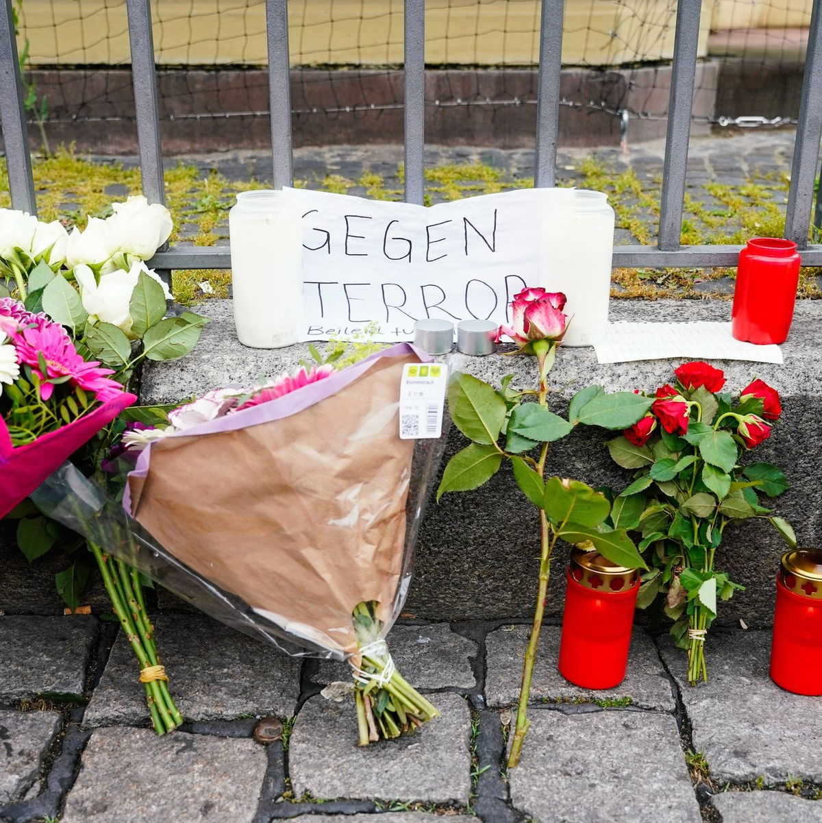 Kerzen, Blumen und ein Blatt Papier mit der Aufschrift «Gegen Terror» stehen am Tatort auf dem Mannheimer Marktplatz. - Foto: Uwe Anspach/dpa