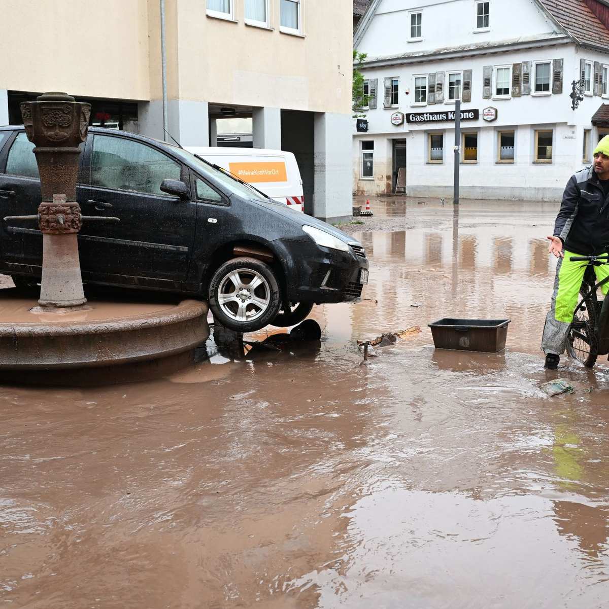 Auf einem Brunnen in Rudersberg steht ein durch ein Hochwasser weggespültes Auto. - Foto: Bernd Weißbrod/dpa