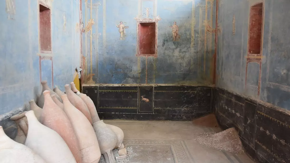 Ein Raum mit blauen Wänden und gemalten weiblichen Figuren ist in Pompeji freigelegt worden. - Bild: Archäologiepark Pompeji/dpa