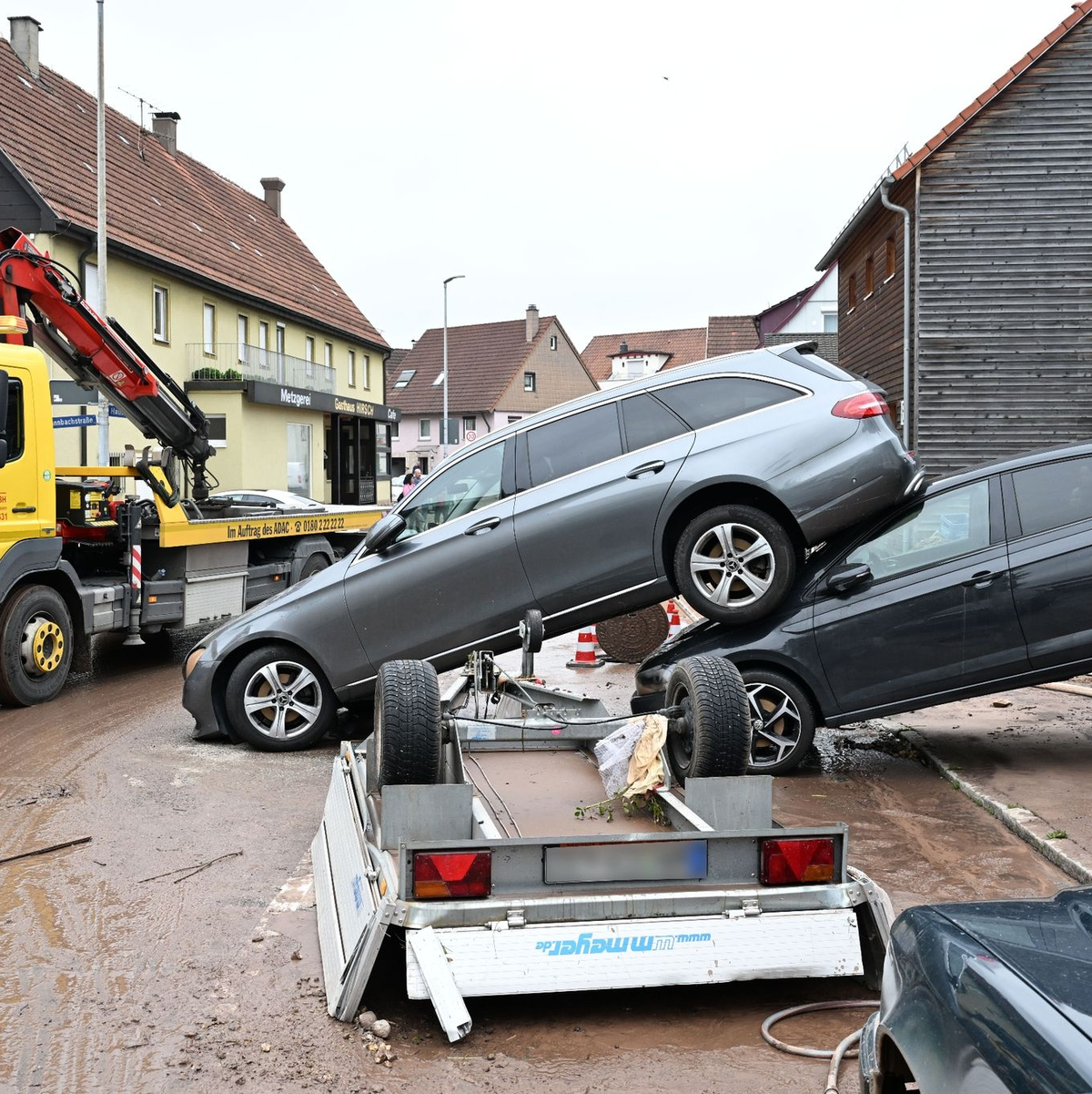 Auf einer Straße in Miedelsbach stehen Fahrzeuge, die durch ein Hochwasser  weggespült wurden. - Foto: Bernd Weißbrod/dpa