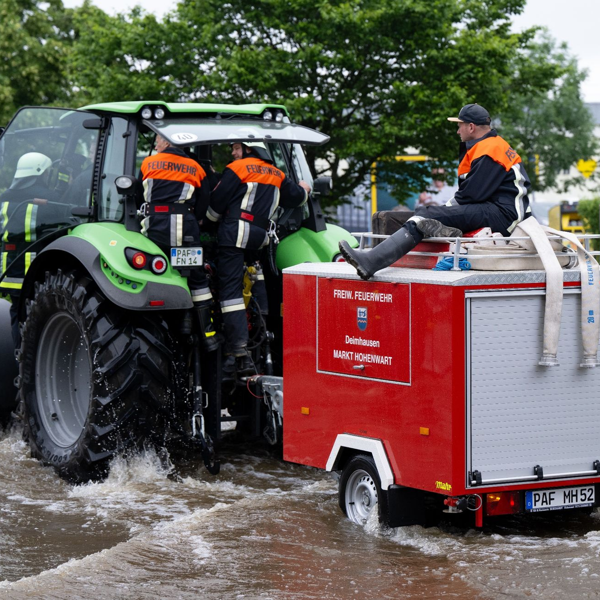 Feuerwehrleute fahren in Reichertshofen über eine überflutete Straße. - Foto: Sven Hoppe/dpa