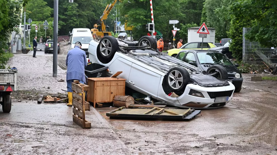 Auf einem Brunnen in Rudersberg steht ein durch Hochwasser weggespültes Auto. - Bild: Bernd Weißbrod/dpa
