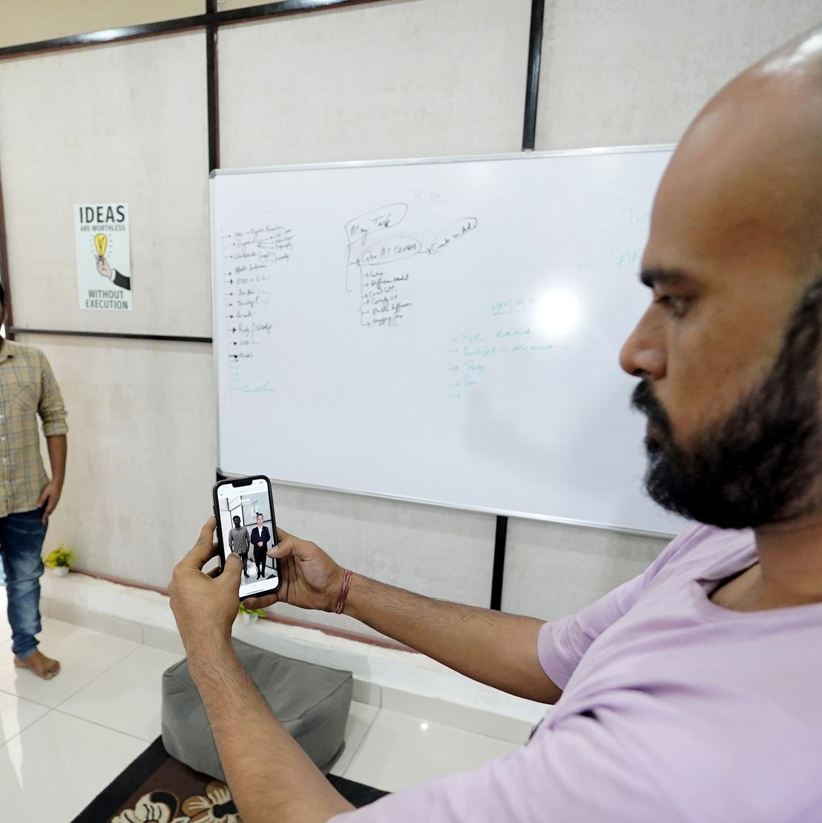 Der Eigentümer der Firma Polymath Synthetic Media Solutions, Divyendra Singh Jadoun, demonstriert mit einem Kollegen wie Leute Selfies mit Politiker-Avataren in ihrer gewohnten Umgebung machen können. - Foto: Himanshu Sharma/dpa