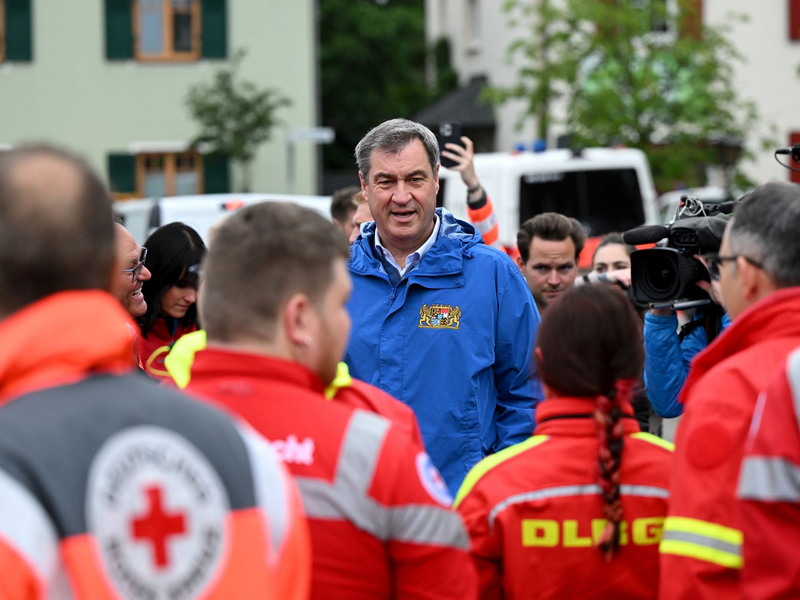 Bayerns Ministerpräsident Markus Söder (M, CSU), spricht zu Einsatzkräften vom Roten Kreuz, DLRG und anderen Rettungskräften bei einer Ortsbesichtigung im vom Hochwasser betroffenen oberbayerischen Reichertshofen. - Foto: Sven Hoppe/dpa