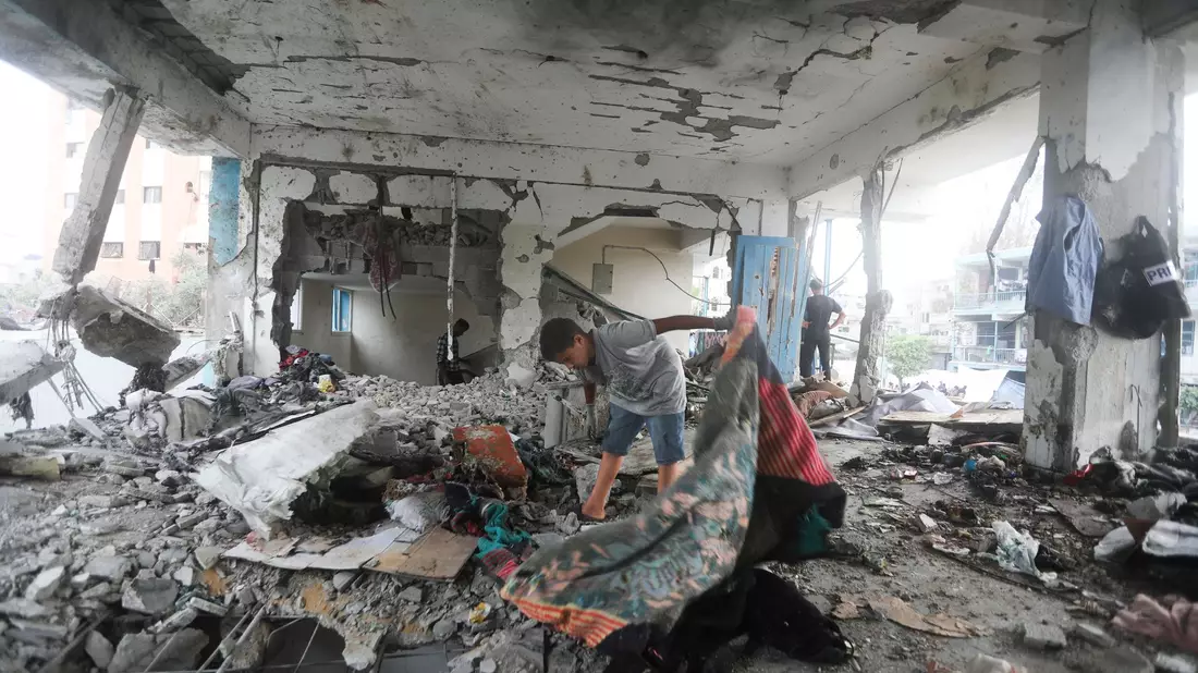 Palästinenser nehmen in einer vom UN-Palästinenserhilfswerk UNRWA betriebenen Schule die Folgen des israelischen Angriffs  in Augenschein. - Bild: Abdel Kareem Hana/AP/dpa
