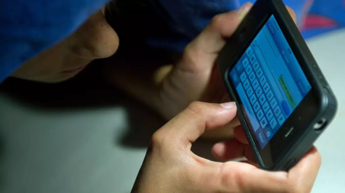 Ein elfjähriger Junge liegt unter der Bettdecke und schreibt auf einem Smartphone eine SMS. Kinder unter 13 Jahren sollten Experten zufolge keinen Zugang zu derartigen Medien haben. - Bild: Patrick Pleul/dpa