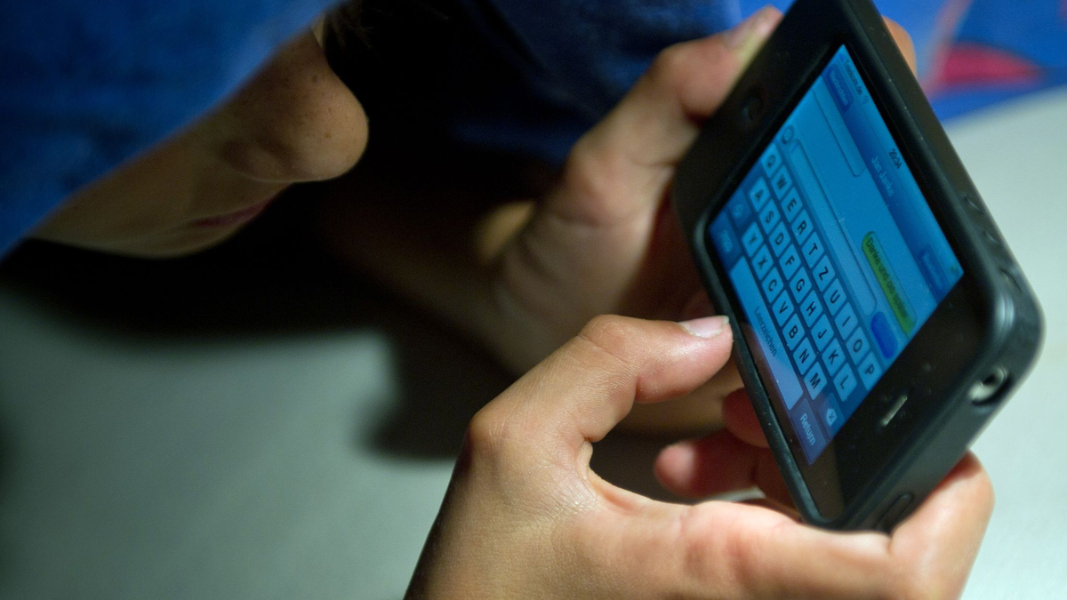 Ein elfjähriger Junge liegt unter der Bettdecke und schreibt auf einem Smartphone eine SMS. Kinder unter 13 Jahren sollten Experten zufolge keinen Zugang zu derartigen Medien haben. - Foto: Patrick Pleul/dpa