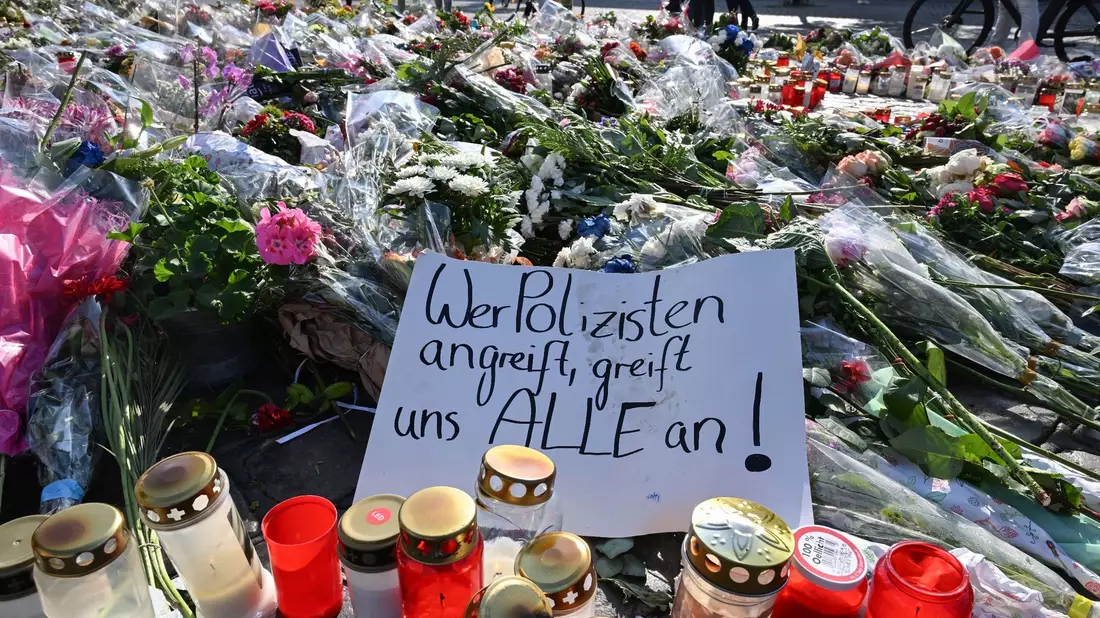 Blumen und Kerzen auf dem Marktplatz in Mannheim zum Gedenken an den getöteten Polizisten. - Bild: Bernd Weißbrod/dpa