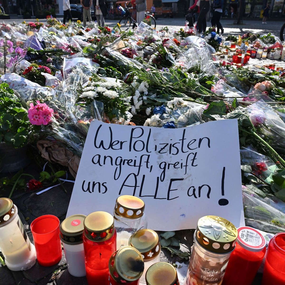 Blumen und Kerzen auf dem Marktplatz in Mannheim zum Gedenken an den getöteten Polizisten. - Foto: Bernd Weißbrod/dpa