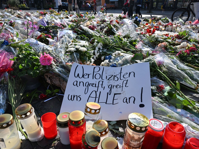Blumen und Kerzen auf dem Marktplatz in Mannheim zum Gedenken an den getöteten Polizisten. - Foto: Bernd Weißbrod/dpa