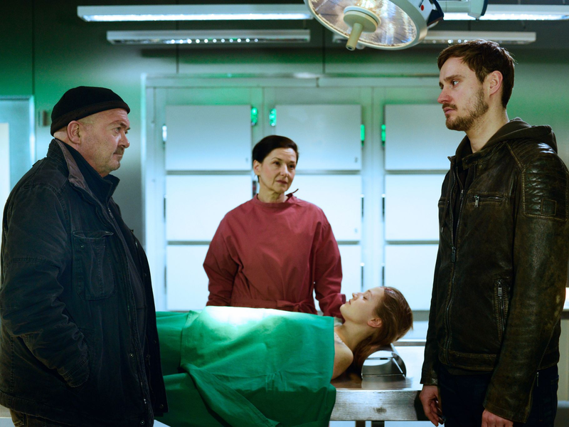 Jan Marxen (Frédéric Brossier, r.) erzählt Dr. Gabriele Simkeit (Eva Sixt, 2.v.l.) und Otto Garber (Florian Martens, l.) von der Medikamentenabhängigkeit seiner toten Freundin. - Foto: Katrin Knoke/ZDF/dpa