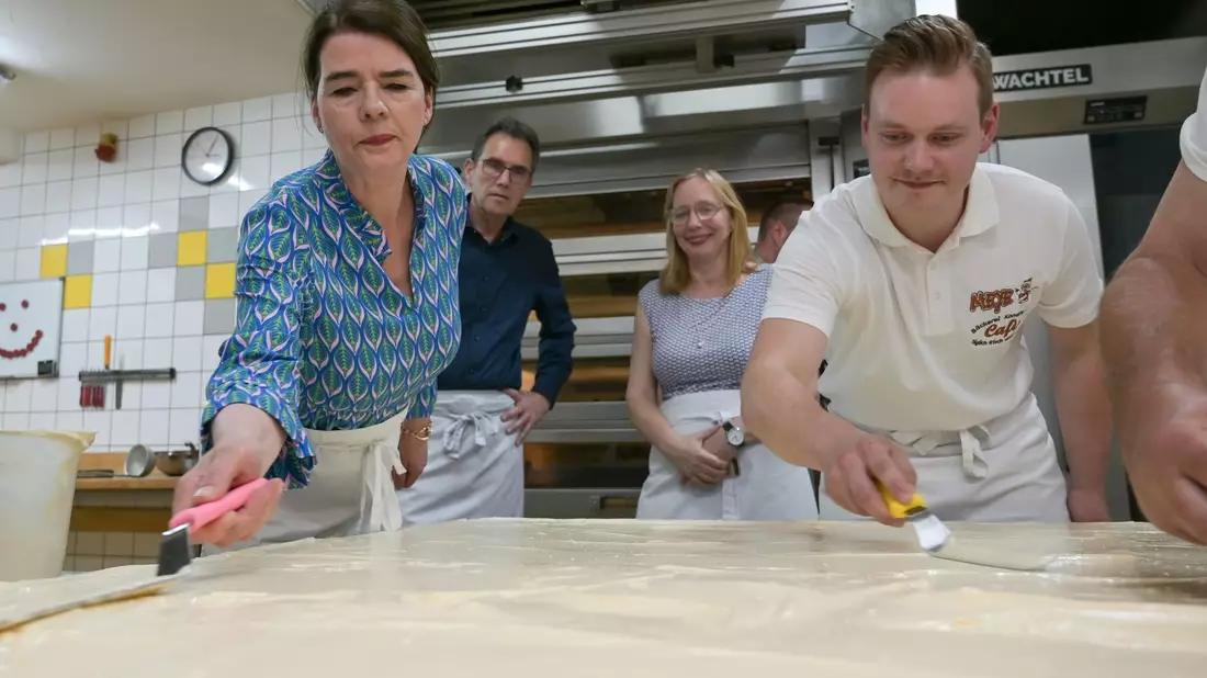 Tagesschau-Sprecherin Susanne Daubner (l) und Bäckermeister Vincent Richter von der Bäckerei Meye verteilen den Sulf-Belag auf dem weltgrößten Mohnkuchen. - Bild: Heiko Rebsch/dpa