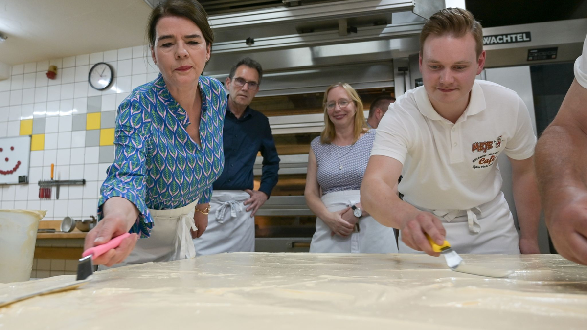 Tagesschau-Sprecherin Susanne Daubner (l) und Bäckermeister Vincent Richter von der Bäckerei Meye verteilen den Sulf-Belag auf dem weltgrößten Mohnkuchen. - Foto: Heiko Rebsch/dpa