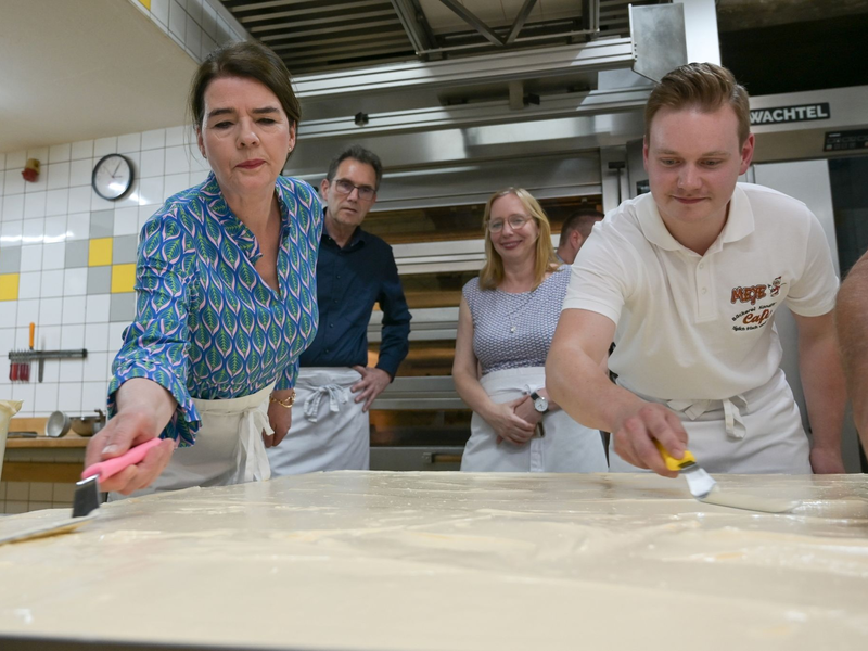 Tagesschau-Sprecherin Susanne Daubner (l) und Bäckermeister Vincent Richter von der Bäckerei Meye verteilen den Sulf-Belag auf dem weltgrößten Mohnkuchen. - Foto: Heiko Rebsch/dpa