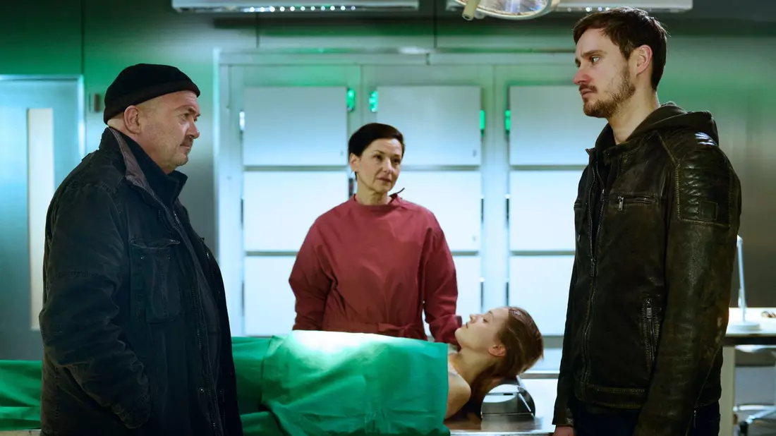 Jan Marxen (Frédéric Brossier, r.) erzählt Dr. Gabriele Simkeit (Eva Sixt, 2.v.l.) und Otto Garber (Florian Martens, l.) von der Medikamentenabhängigkeit seiner toten Freundin. - Bild: Katrin Knoke/ZDF/dpa