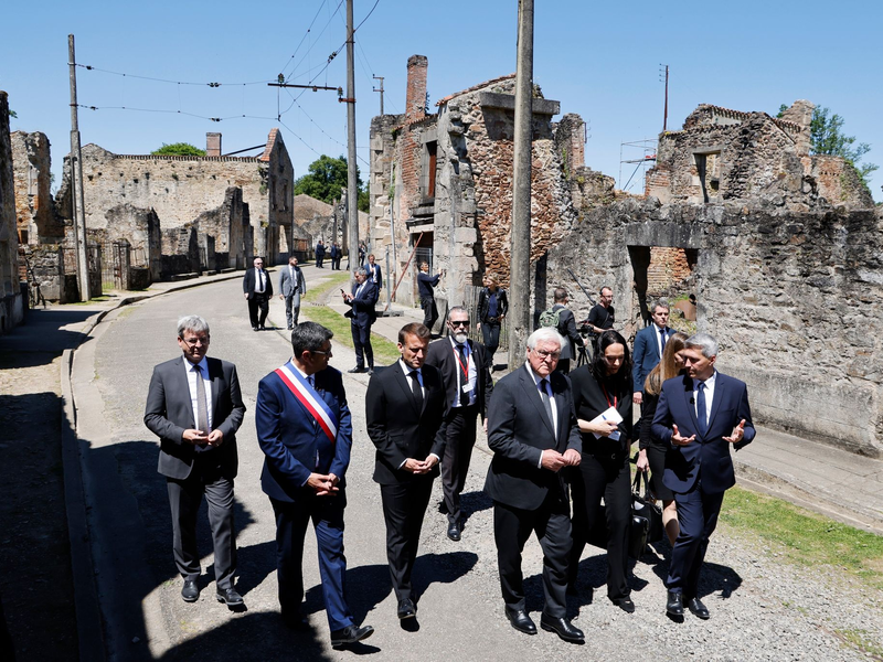 Der französische Präsident Emmanuel Macron und der deutsche Bundespräsident Frank-Walter Steinmeier gehen an Ruinen in Oradour-sur-Glane vorbei. - Foto: Ludovic Marin/AFP Pool/AP/dpa