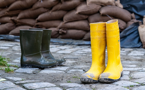 Gummistiefel stehen in der Altstadt vor Sandsäcken. Der Hochwassernachrichtendienst geht von einem baldigen Ende der Hochwasserlage in Bayern aus. - Foto: Armin Weigel/dpa