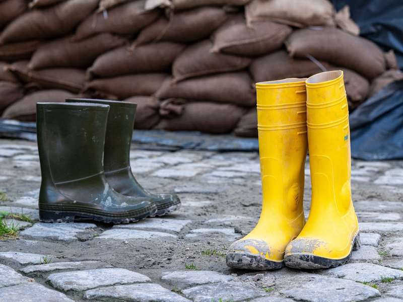 Gummistiefel stehen in der Altstadt vor Sandsäcken. Der Hochwassernachrichtendienst geht von einem baldigen Ende der Hochwasserlage in Bayern aus. - Foto: Armin Weigel/dpa