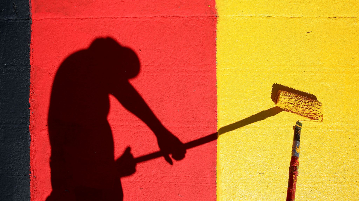 Heute Abend geht es los! Ein Helfer lackiert Kurvensteine in den Farben Schwarz-Rot-Gold. - Foto: Jan Woitas/dpa