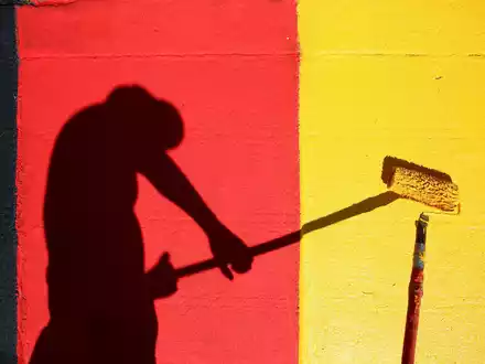 Heute Abend geht es los! Ein Helfer lackiert Kurvensteine in den Farben Schwarz-Rot-Gold. - Foto: Jan Woitas/dpa