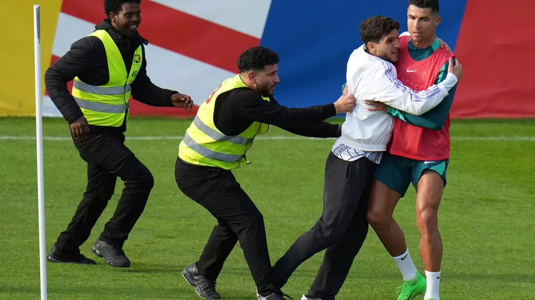 Ein Fan sprintet in Gütersloh auf den Trainingsplatz und umarmt Portugals Superstar Cristiano Ronaldo. - Bild: Hassan Ammar/AP/dpa