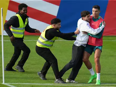 Ein Fan sprintet in Gütersloh auf den Trainingsplatz und umarmt Portugals Superstar Cristiano Ronaldo. - Foto: Hassan Ammar/AP/dpa