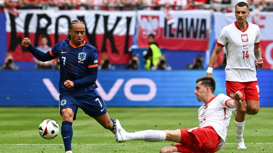 Der Niederländer Xavi (l) und Polens Taras Romanczuk kämpfen um den Ball. - Bild: Sina Schuldt/dpa