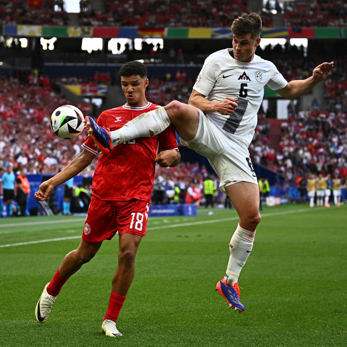 Dänemarks Alexander Bah und Sloweniens Jaka Bijol (r) kämpfen um den Ball. - Foto: Tom Weller/dpa