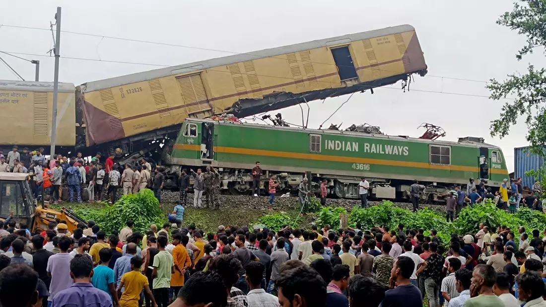 Schaulustige beobachten die Arbeit von Rettungskräften, nachdem ein Güterzug in der Nähe des Bahnhofs von New Jalpaiguri im indischen Bundesstaat Westbengalen einen Personenzug gerammt hat. - Bild: Diptendu Dutta/AP/dpa