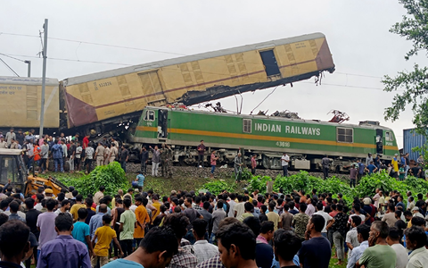Schaulustige beobachten die Arbeit von Rettungskräften, nachdem ein Güterzug in der Nähe des Bahnhofs von New Jalpaiguri im indischen Bundesstaat Westbengalen einen Personenzug gerammt hat. - Foto: Diptendu Dutta/AP/dpa
