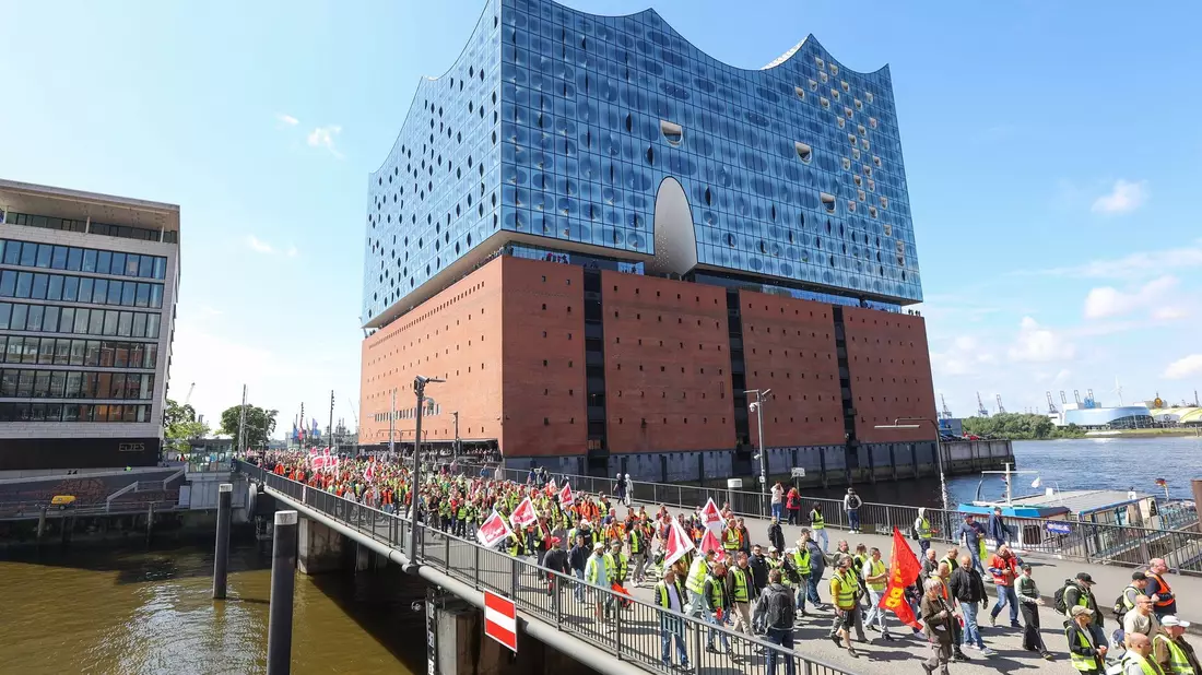 Streikende Hafenarbeiter ziehen bei einer Demonstration an der Hamburger Elbphilharmonie entlang. - Bild: Bodo Marks/dpa