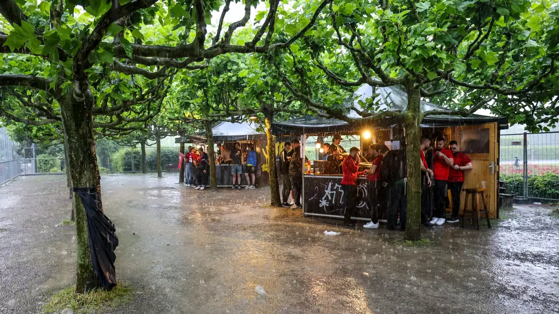 Zumindest ein bisschen Schutz: Fussballfans in Dortmund haben sich beim strömenden Regen an Imbissbuden untergestellt. - Bild: Christoph Reichwein/dpa