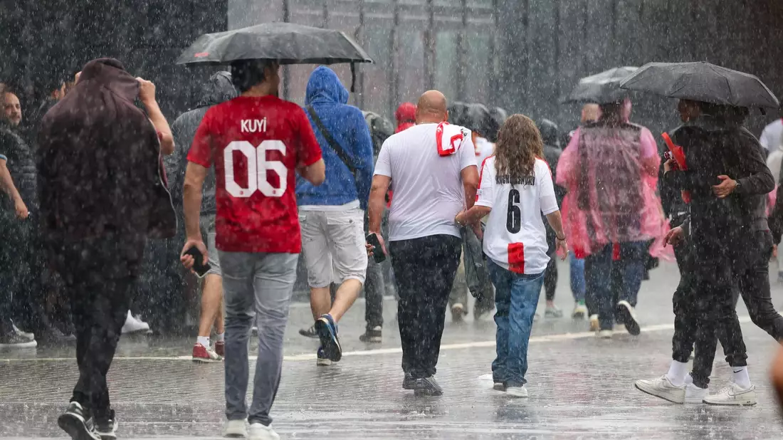 Das haben sie sich sicherlich anders vorgestellt: Fussballfans in Dortmund laufen im strömenden Regen zum Stadion. - Bild: Christoph Reichwein/dpa