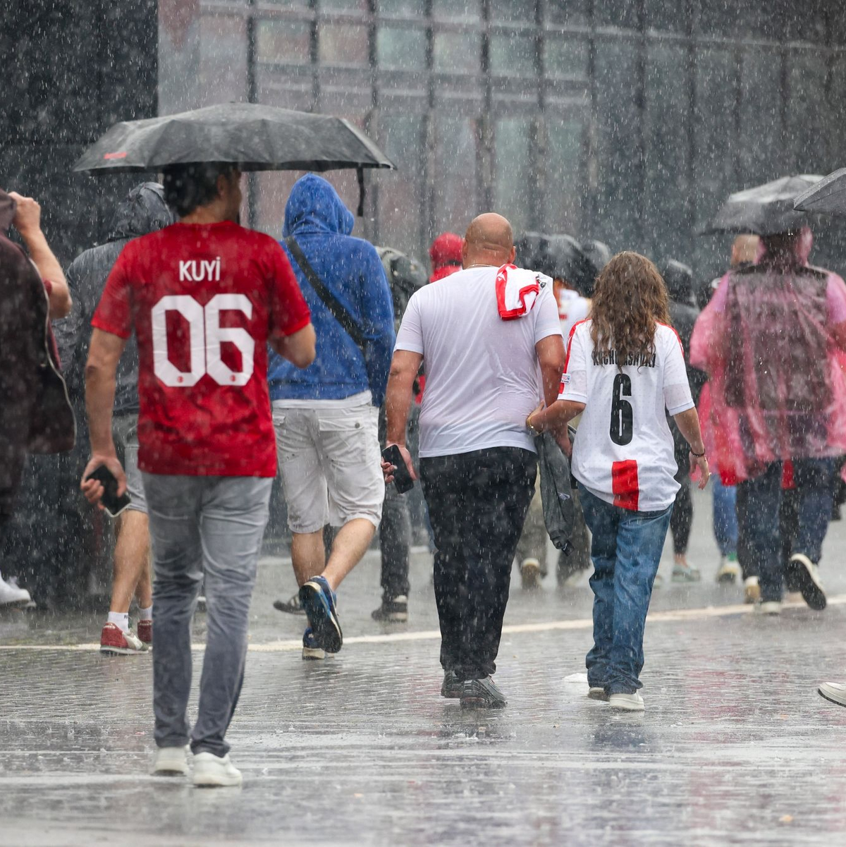 Das haben sie sich sicherlich anders vorgestellt: Fussballfans in Dortmund laufen im strömenden Regen zum Stadion. - Foto: Christoph Reichwein/dpa